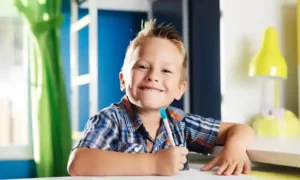 Enfant souriant et confiant installé à son bureau.